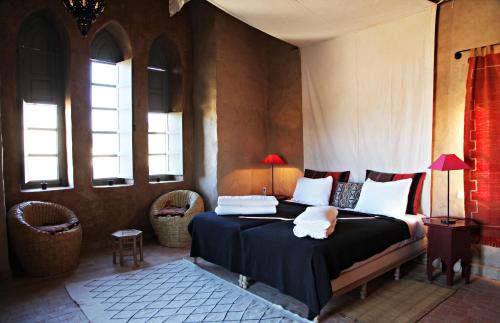 a bedroom with a bed in a room with windows at Le moulin in Taroudant