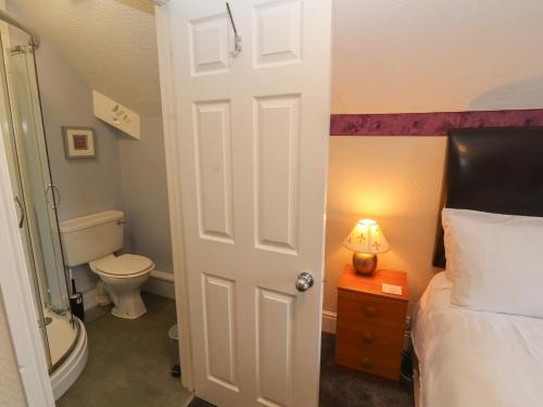 a bathroom with a bed and a toilet and a door at Fern Lee in Carlisle