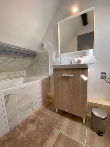 une salle de bain avec un lavabo, une baignoire et un miroir dans l'établissement L’Embrun, à Dieppe