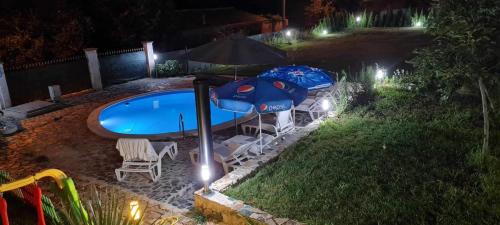 a swimming pool with two umbrellas and chairs next to a swimming pool at Sunshine villa Dzhigurovo in Sandanski