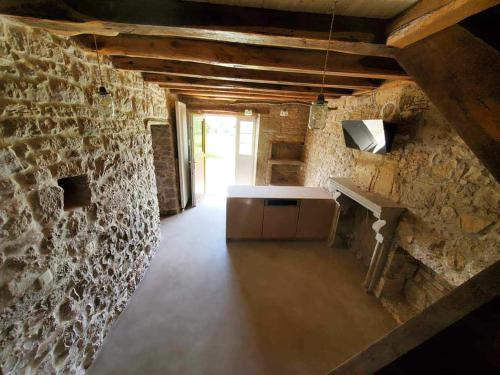Habitación con pared de piedra, encimera y mesa. en Le Paradis de Nina 