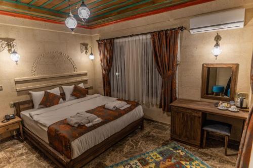 a bedroom with a bed with a desk and a mirror at Cordial Cappadocia Hotel in Ortahisar