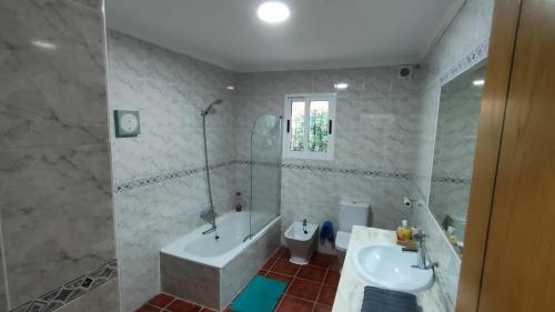 een badkamer met een bad, een wastafel en een toilet bij Villa Pilarín in Málaga