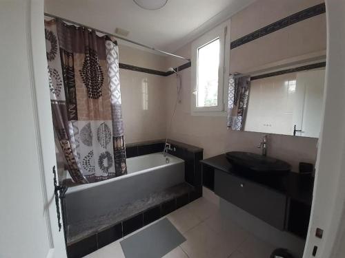 une salle de bain avec une baignoire et un lavabo dans l'établissement Villa avec piscine, à Capbreton