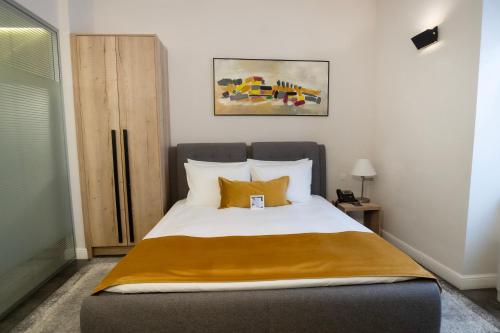 a bedroom with a large bed with yellow pillows at The Dome Hotel in Satu Mare