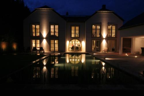 une maison avec une piscine la nuit dans l'établissement B&B White Pearl, à Mullerthal