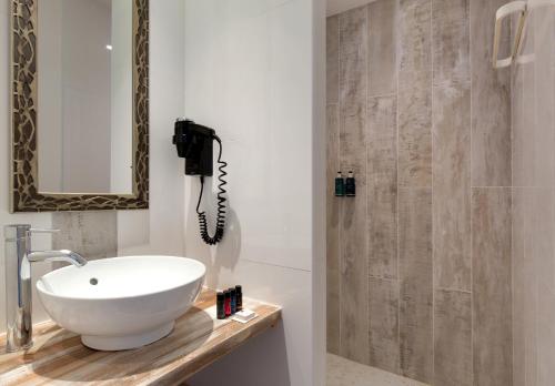 a bathroom with a sink and a shower with a phone at Vila De La Mar & Spa in Saintes-Maries-de-la-Mer