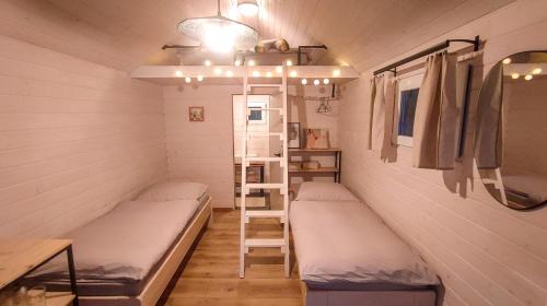 um pequeno quarto com duas camas e uma escada em Tiny House em Chvalšiny