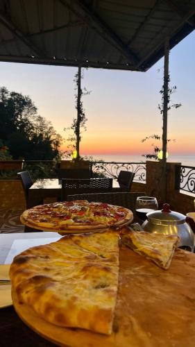 two pizzas sitting on a table in front of the ocean at Goga Guest House in Kvariati