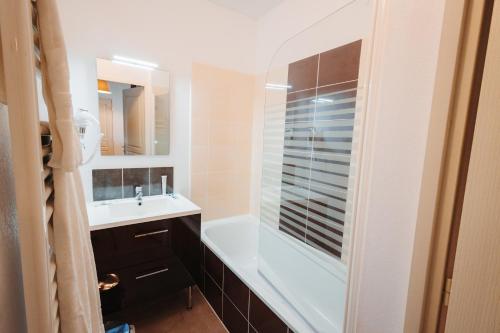 a bathroom with a white tub and a sink at Résidence Domaine de la Vallée d'Ax - Location à la nuit, linge inclus in Ax-les-Thermes