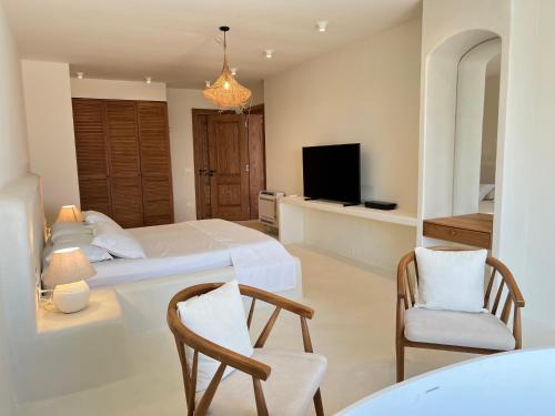 a bedroom with a bed and a tv and chairs at White Pearl Villa in Dhërmi