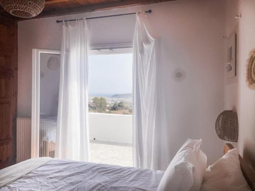 um quarto com uma cama e uma janela com vista em The Mykonos House - Newly Renovated Villa Near Town em Míconos