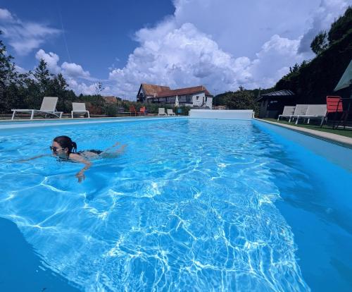 Logis Auberge du Relais في Berenx: A young girl swimming in a large swimming pool