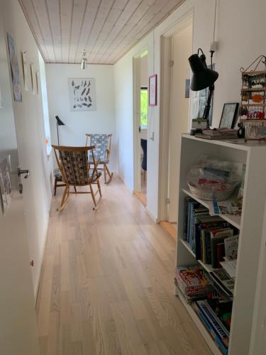 un pasillo con una silla y una estantería con libros en Tusindfrugt B&B, en Store Heddinge