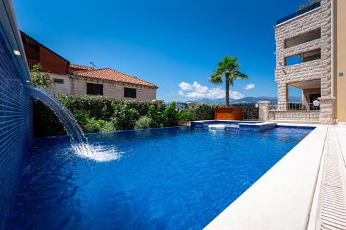 a swimming pool with a water fountain in a yard at Raicevic Residence in Tivat