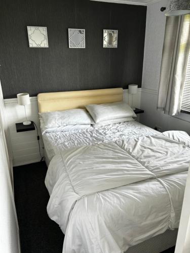 a bedroom with a large bed with white sheets at 2 Bedroom Chalet Close to Beach in Hemsby