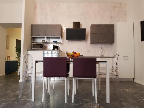 - une cuisine avec une table, des chaises et un bol de fruits dans l'établissement Casa Gaia, à Naples