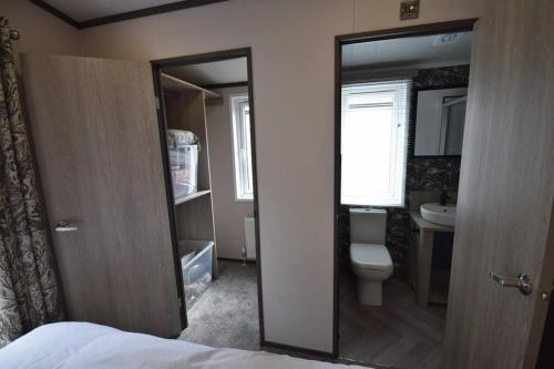 a small bathroom with a toilet and a sink at Riverwood Lodge, The Boulevard, Seal Bay, Selsey in Selsey
