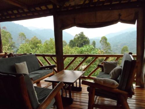 een veranda met banken en een tafel en uitzicht op de bergen bij Buhoma Community Haven lodge 