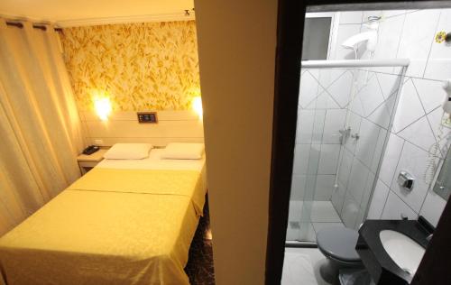 a small room with two beds and a shower at Hotel Três Fronteiras in Foz do Iguaçu