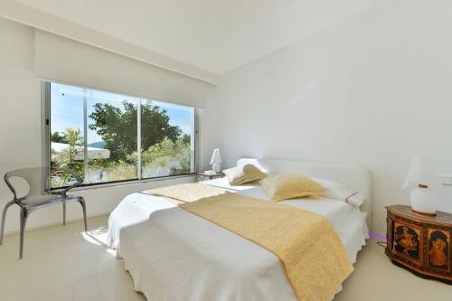 a white bedroom with a bed and a large window at Mordern Villa - Sea view - Near Eivissa old town in Can Furnet