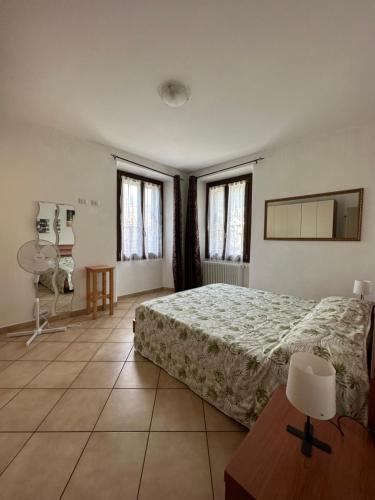 a bedroom with a bed and a table and windows at Appartamenti Sole e Lago in Gravedona