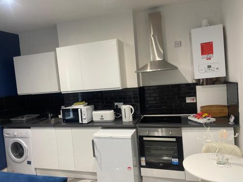 uma cozinha com armários brancos e um forno com placa de fogão em Modern Spacious 2 Bedroom Apt em Rowley Regis