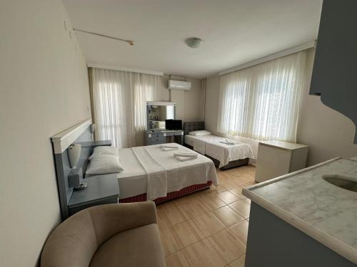 a hotel room with two beds and a chair at Cicek Apart Hotel in Çeşme