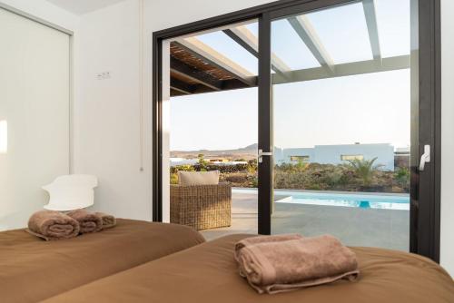 two beds in a bedroom with a view of a pool at Villa Alfa by FuerteventuraVillas in Lajares