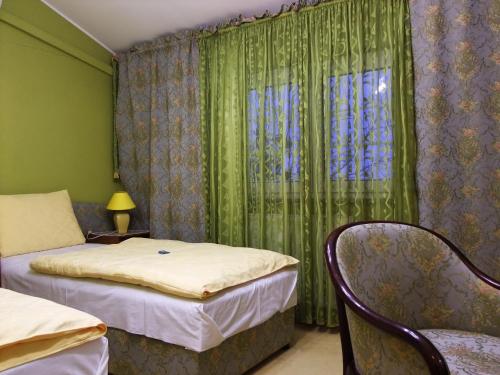 1 dormitorio con 2 camas y una ventana con cortinas verdes en Bed & Breakfast Vila Stanišić, en Požega