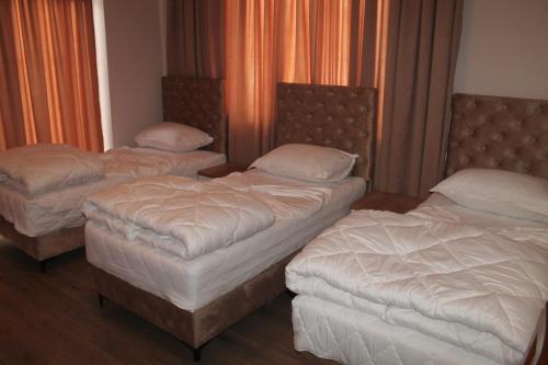 three twin beds in a room with orange curtains at Hotel Princ in Shkodër