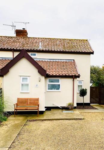 a white house with a bench in front of it at Baytree Cottage Framlingham in Framlingham