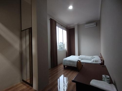 a room with two beds and a table and a window at Saira Hotel dan Homestay Syariah in Sleman
