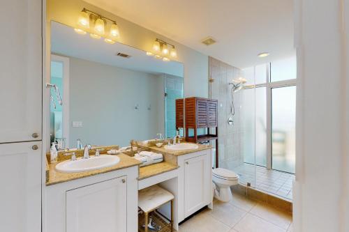 a bathroom with two sinks and a toilet and a large mirror at Emerald By the Sea 1214 Sea for Miles in Galveston