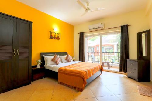 um quarto com paredes amarelas, uma cama e uma varanda em Royale Holiday Villa - 4BHK, Baga em Baga
