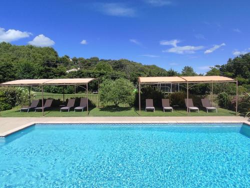 a swimming pool with chairs and umbrellas at Les Grandes Terres - Gîtes & SPA in Mérindol