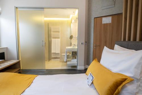 a bedroom with a white bed with yellow pillows and a bathroom at The Dome Hotel in Satu Mare