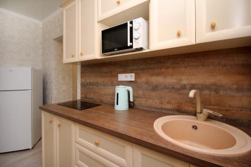 a kitchen counter with a sink and a microwave at Your Home Away from Home in Almaty