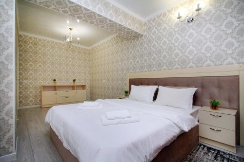 a bedroom with a large bed with white sheets at Your Home Away from Home in Almaty