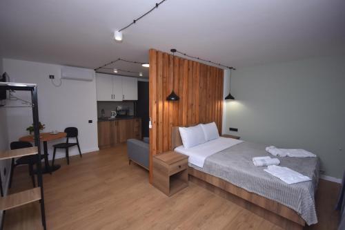 a bedroom with a bed and a desk and a kitchen at Pine Aparthotel in Shekvetili