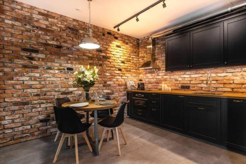 cocina con pared de ladrillo, mesa y sillas en Stunning loft-style apartment en Varsovia