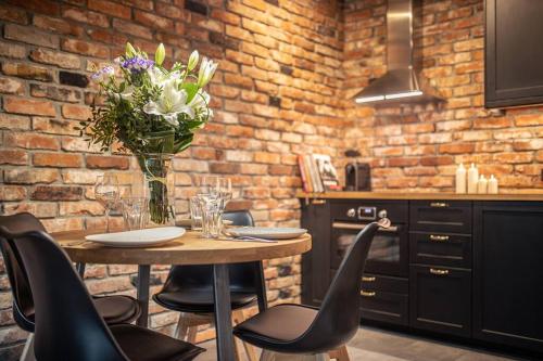 una cocina con una mesa con sillas y un jarrón de flores en Stunning loft-style apartment en Varsovia