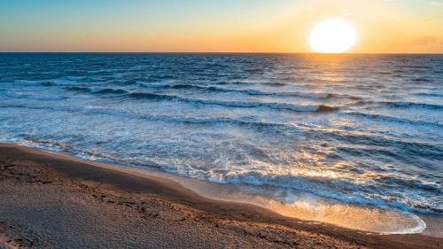 una puesta de sol sobre el océano con una playa en Willa Karolinka, en Łeba