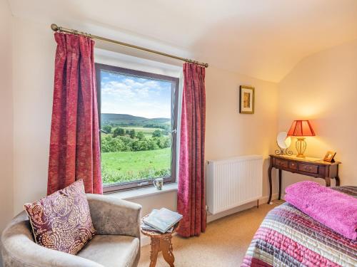 a bedroom with a window and a couch and a chair at Pennine View in Long Marton