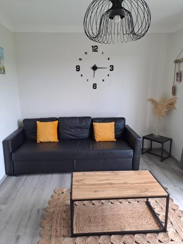 a living room with a black couch and a clock on the wall at Agréable T2 Classé 3 étoiles, refait à neuf, dans quartier calme in Rodez