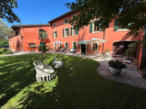 einen grünen Hof mit einem Gebäude mit einer Statue im Gras in der Unterkunft Relais Corte Bercelli in Valeggio sul Mincio