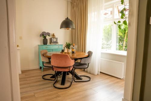 ein Esszimmer mit einem Tisch, Stühlen und einem Fenster in der Unterkunft Kapiteinshuisje in Harderwijk