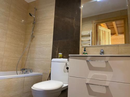 ein Badezimmer mit einem WC, einem Waschbecken und einem Spiegel in der Unterkunft Bursztynowe Domki in Sarbinowo
