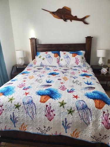 a bed with a comforter with fish on it at Villa Roberto Vista Hermosa in Sardinal