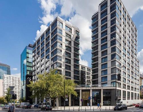 een hoog wit gebouw met auto's geparkeerd voor het bij MENNICA RESIDENCE PATRONUS Apartments in Warschau